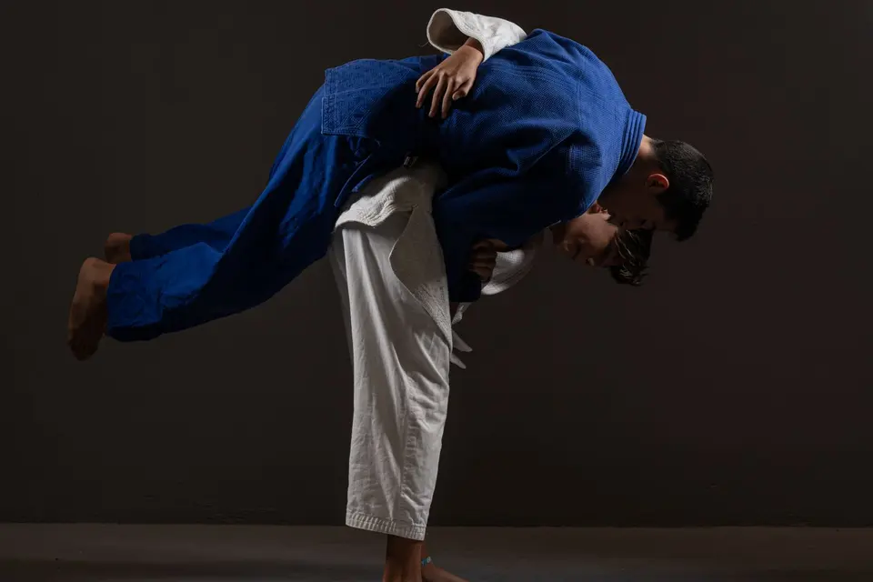 Judocas de judogi azul e branco no meio de uma projeção