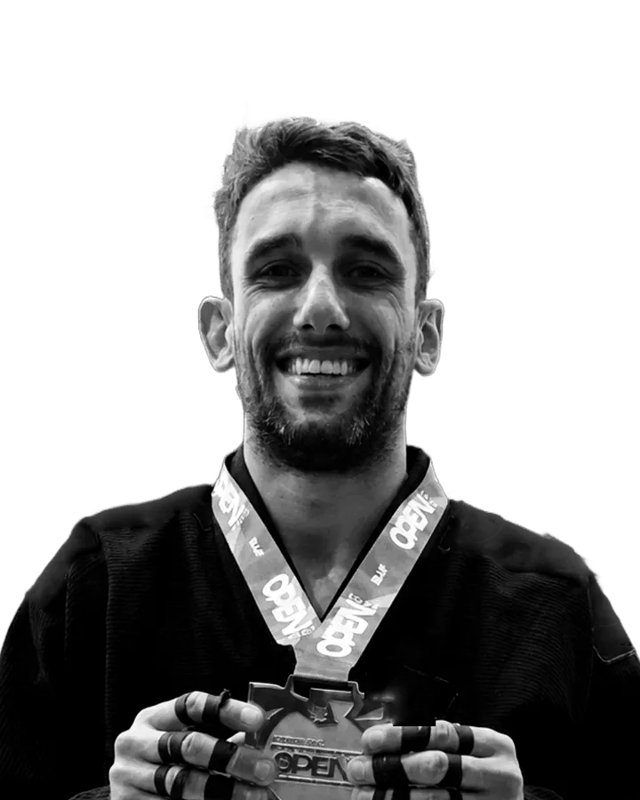 Rhaue Scuzziato sorrindo, de kimono preto, segurando com os dedos enfaixados a medalha que leva no pescoço